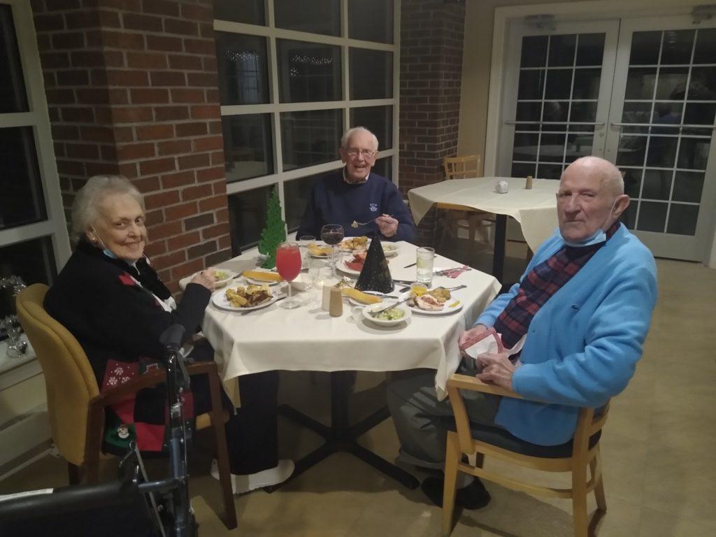 3 smiling residents enjoying new year's eve dinner
