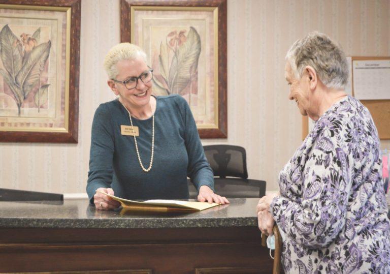 woman resident getting assistance from staff member at front desk